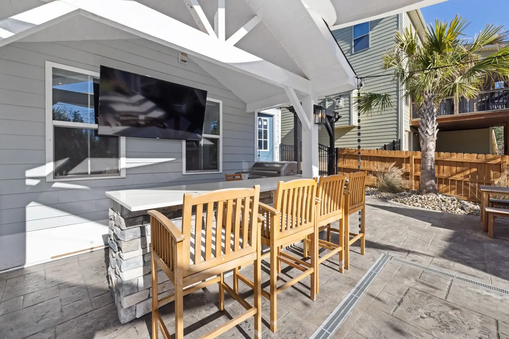 Covered patio with outdoor TV entertainment wall, stone bar and seating