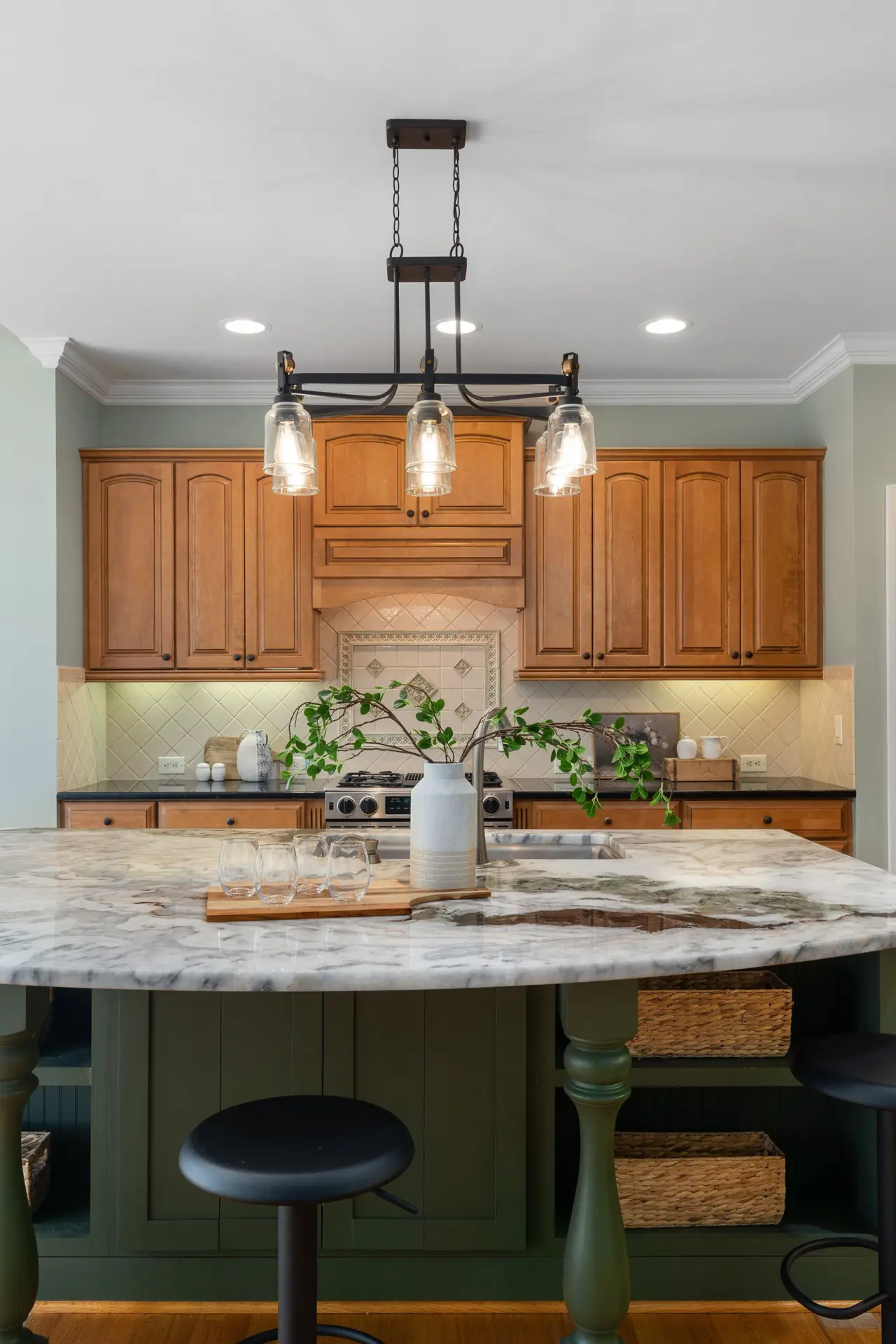 Kitchen with a rounded island, warm wood cabinetry and pendant lights